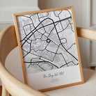 Where it all began poster met vierkante stadskaart in grijs, in houten lijst op een stoel